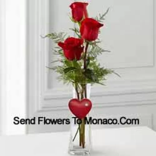 3 Red Roses In A Glass Vase Having A Small Heart Attached To It